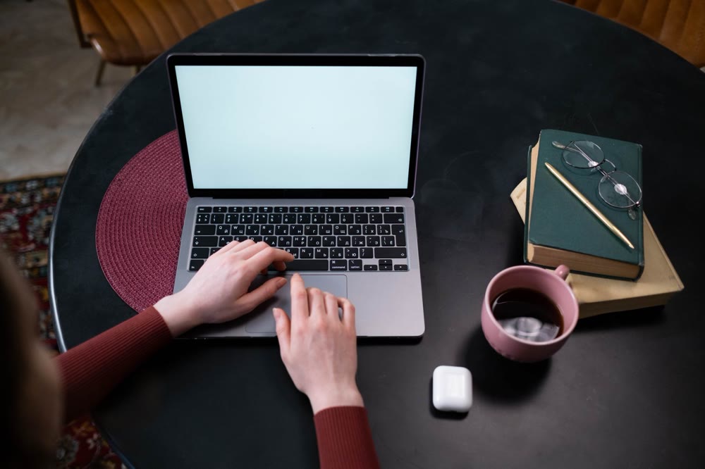 ノートPCのトラックパッドに両手を置いて、画面を操作している手元