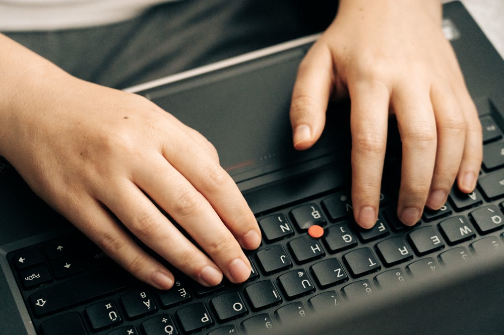 ノートPCのキーボードに両手を置き、キーを押して動作を確かめている手元