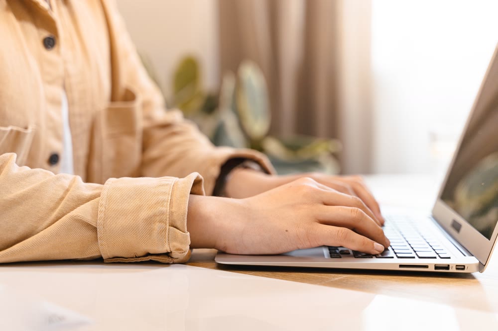 ノートPCのキーボードに両手を置いて、画面に向かって操作している手元