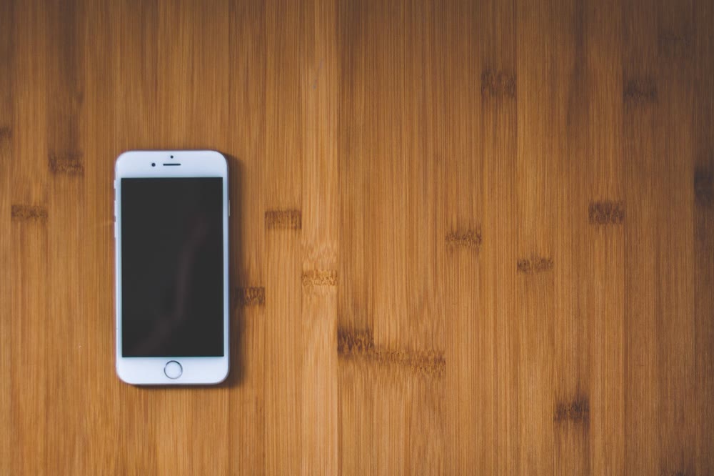 木の机の上にスマートフォンが1台だけ置かれている様子