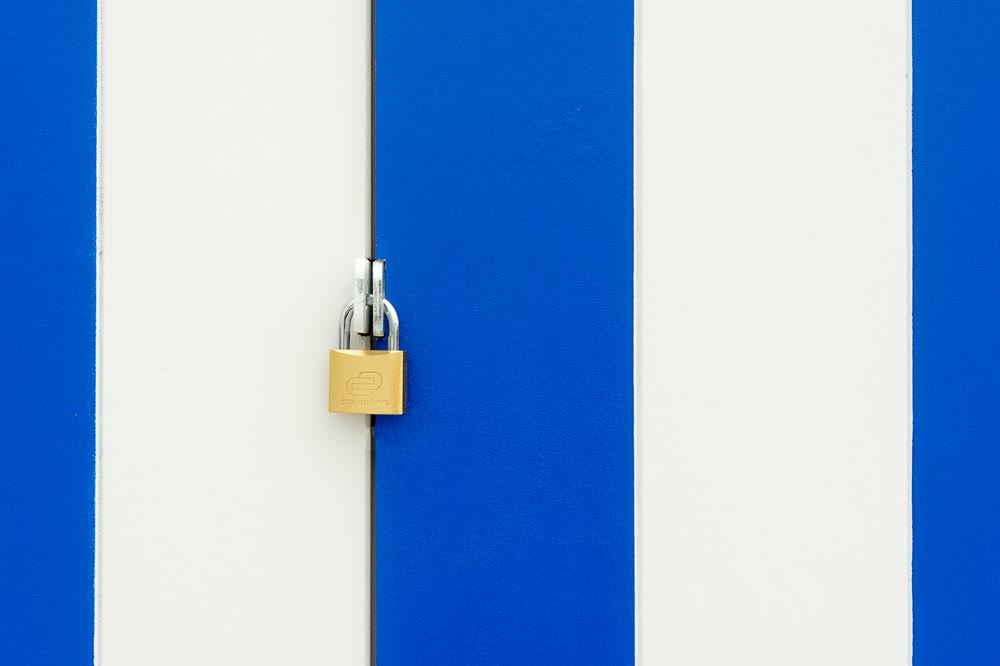 青と白の縞模様の扉に取り付けられた金色の南京錠のクローズアップ