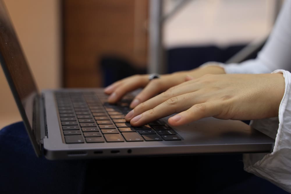 ノートパソコンのキーボードに両手を置いて入力している手元
