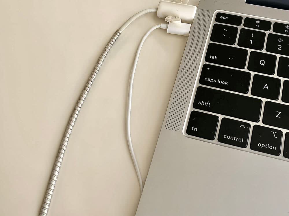 机の上のノートパソコンに、充電ケーブルがつながっている様子