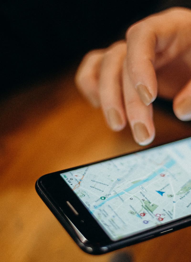 テーブルの上で、スマートフォンの地図アプリを指で操作している手元