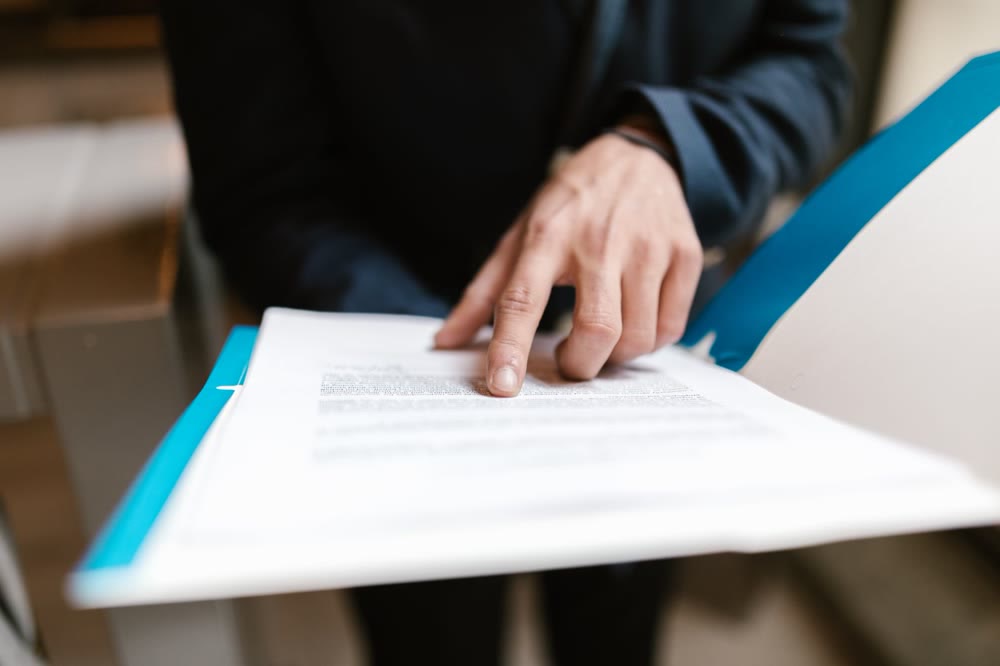 テーブルに広げた書類の上に指を置いて、内容を確かめている手元
