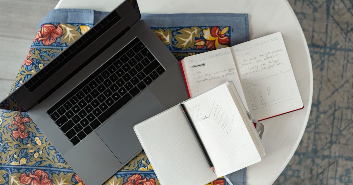 机の上に開いたノートPCと2冊の手帳が並び、サイトの管理項目を点検する前の様子